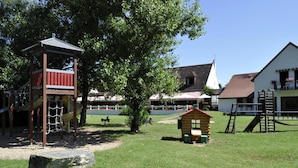 Un parque infantil con una estructura de escalada, una casita y columpios.