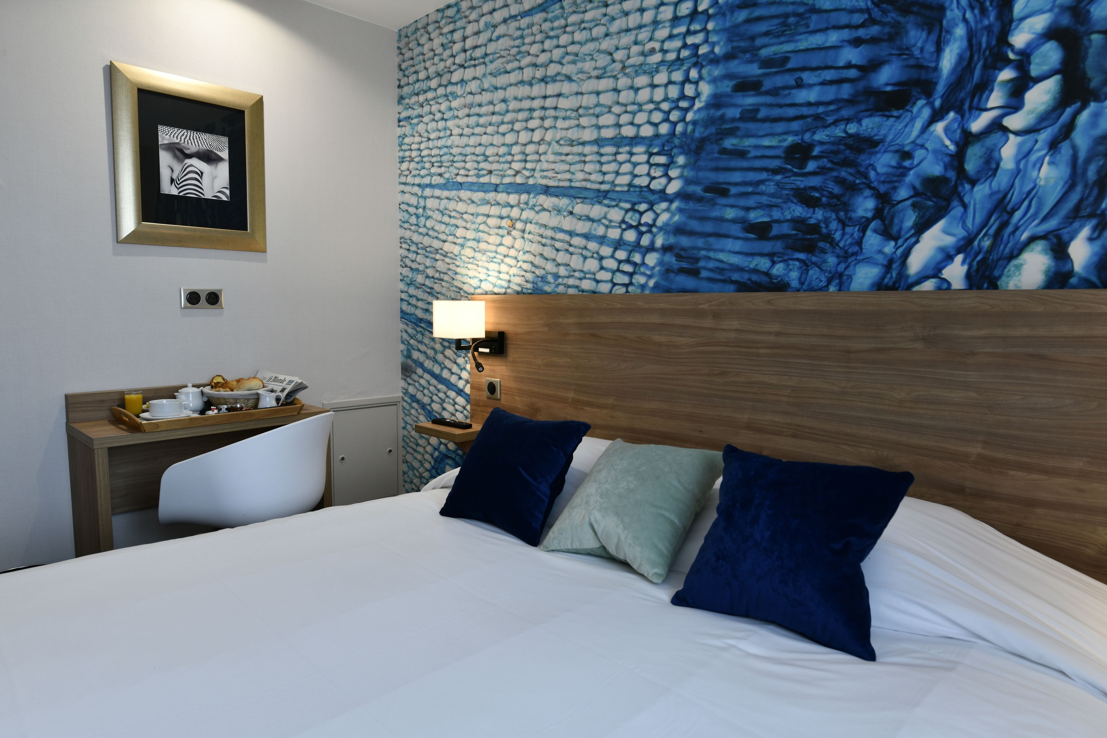 Een hotelkamer met een bed, een bureau en een muur met een structuur.
