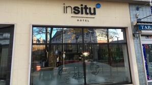 The exterior of the Insitu Hotel with a large glass facade reflecting the surrounding architecture.