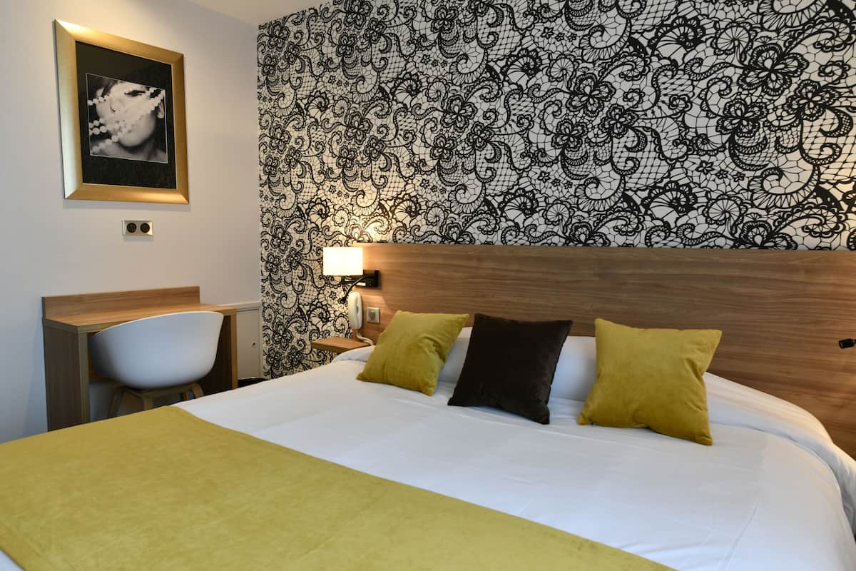 A hotel room with a bed, a desk, and a chair.