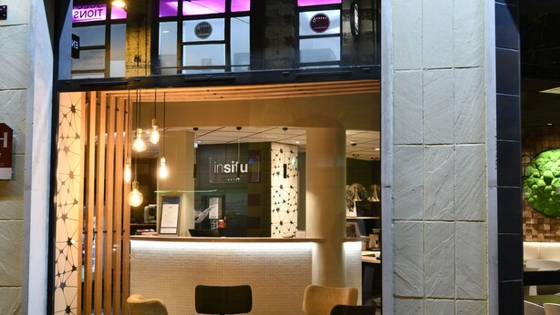 A modern interior with a reception desk, seating area, and a visible sign reading "INSITU".