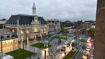 A historic building with a prominent clock tower, a tram line, and a busy street with cars.