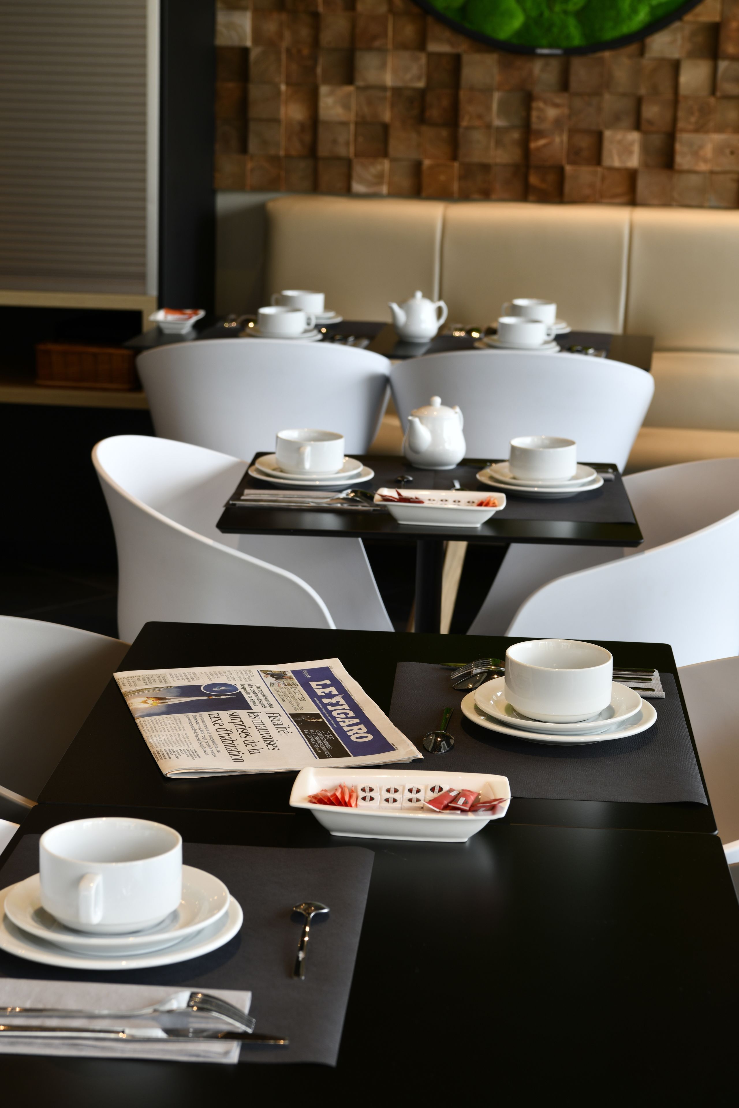 A dining area with a table set for two, including white cups, saucers, a teapot, and cutlery.