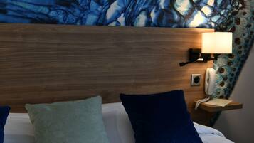 A hotel room with a wooden headboard, a bedside lamp, a telephone, and two pillows.