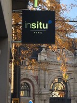 Señal de Insitu Hotel con un edificio clásico al fondo.