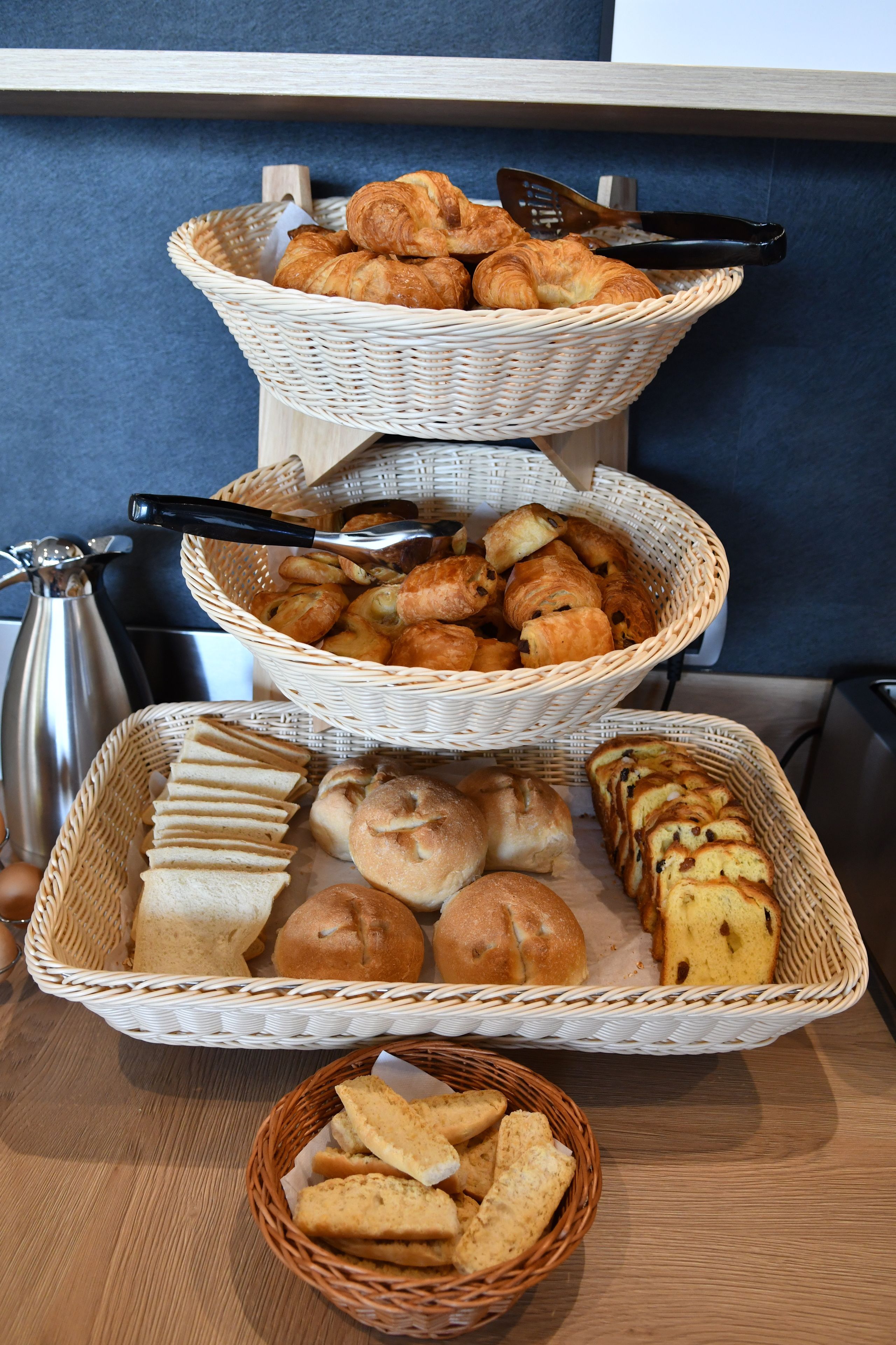 Une table sur laquelle se trouvent trois paniers en osier contenant divers produits de boulangerie.