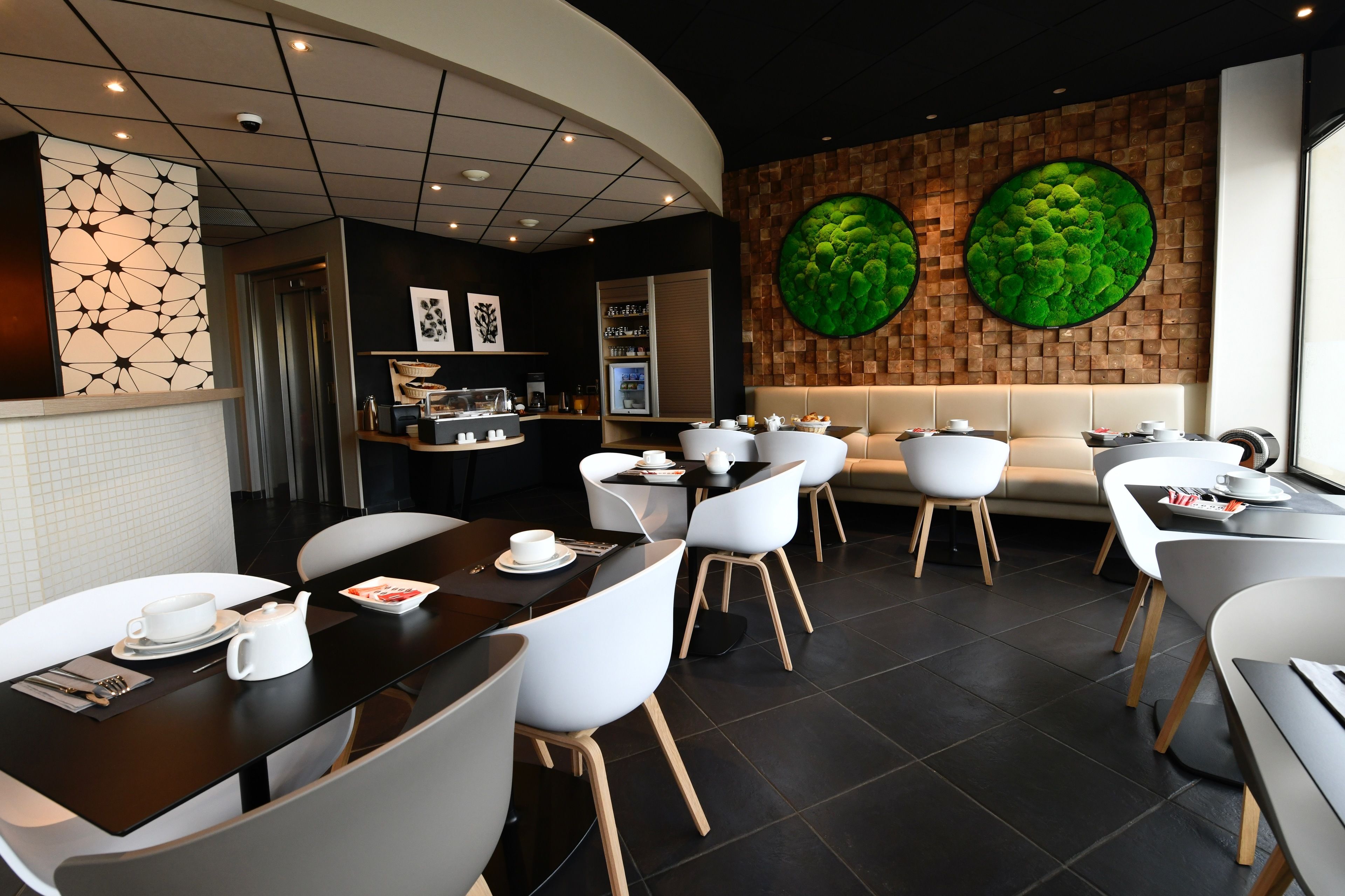 Un restaurante moderno con techo curvo, sillas blancas y una zona central de estar con sofá.