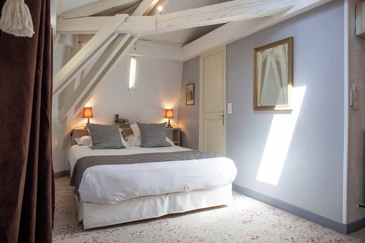 Une chambre à coucher avec un lit, deux lampes de chevet, une fenêtre et une porte.