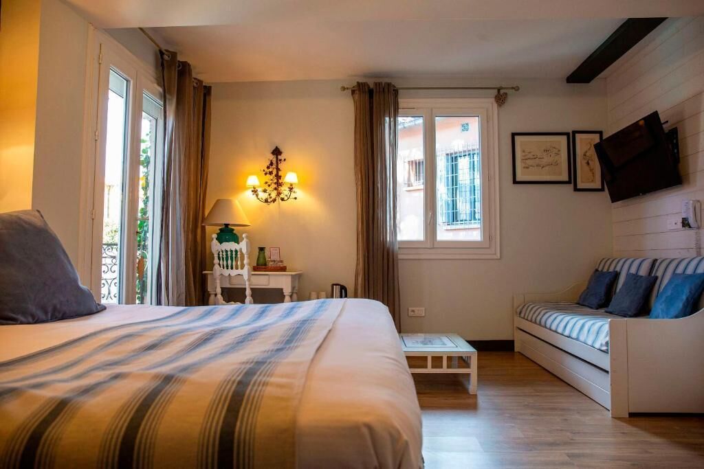 Un dormitorio con una cama, un sofá, una mesita, una lámpara y un televisor en la pared.