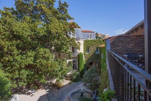 A courtyard with a fountain, a tree, and a building with a stone facade.