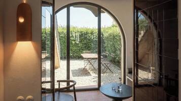 Une pièce dotée d’une grande porte en verre en arc de cercle qui donne sur un patio extérieur avec une table et des chaises.