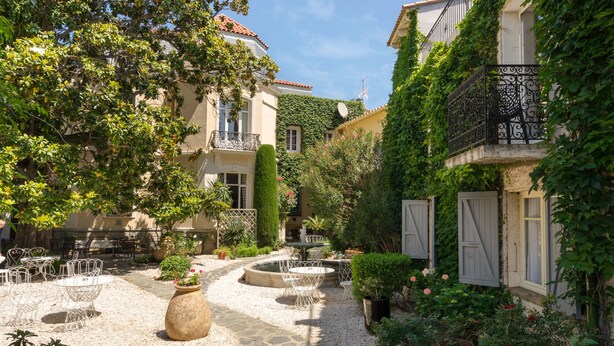 A courtyard with outdoor seating, a fountain, and lush greenery. - Hôtel La Casa Païral (Collioure)