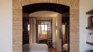 A hotel room with a brick archway, a bed, a desk, and a bookshelf. - Hôtel La Casa Païral (Collioure)