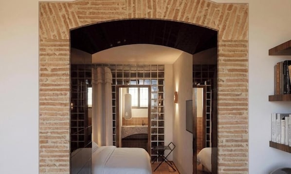 A hotel room with a brick archway, a bed, a desk, and a bookshelf. - Hôtel La Casa Païral (Collioure)