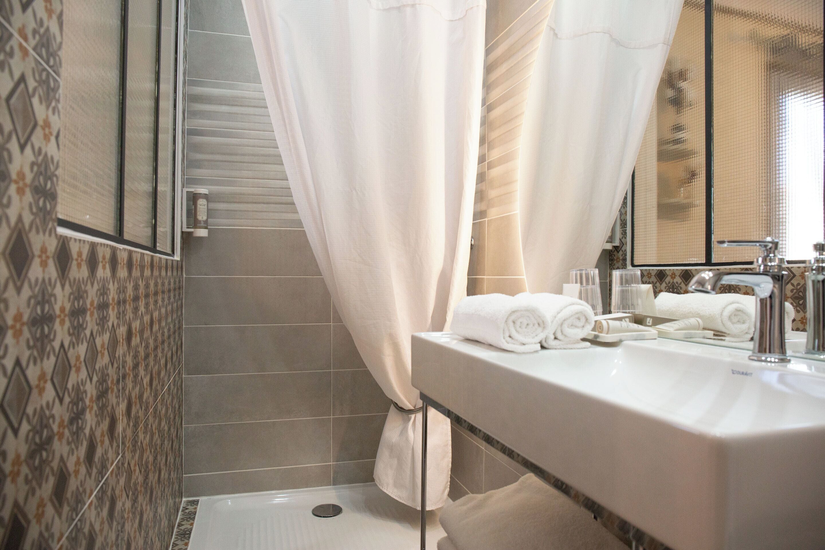 Un baño con ducha, lavamanos y espejo, y toallas.