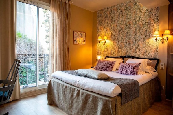Una habitación de hotel con cama, balcón y un papel tapiz estampado.