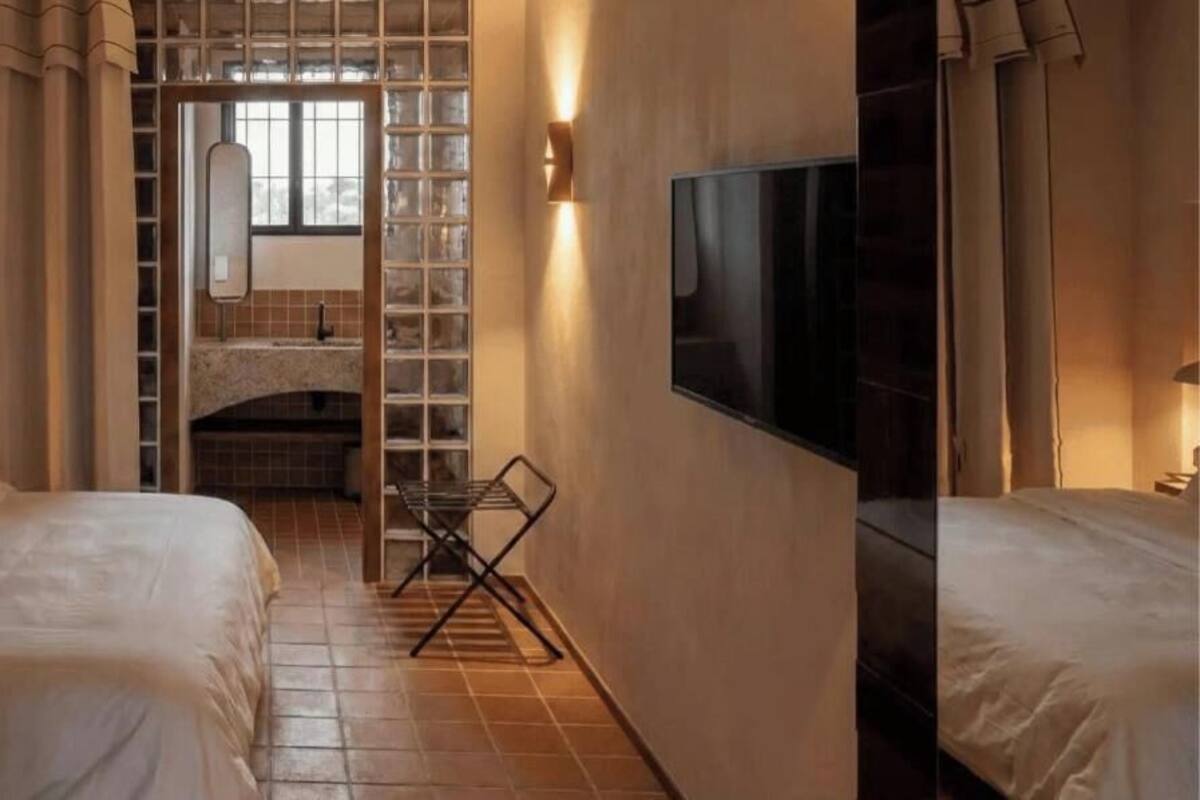 Une chambre d’hôtel avec deux lits, une télévision, une cheminée et une fenêtre.