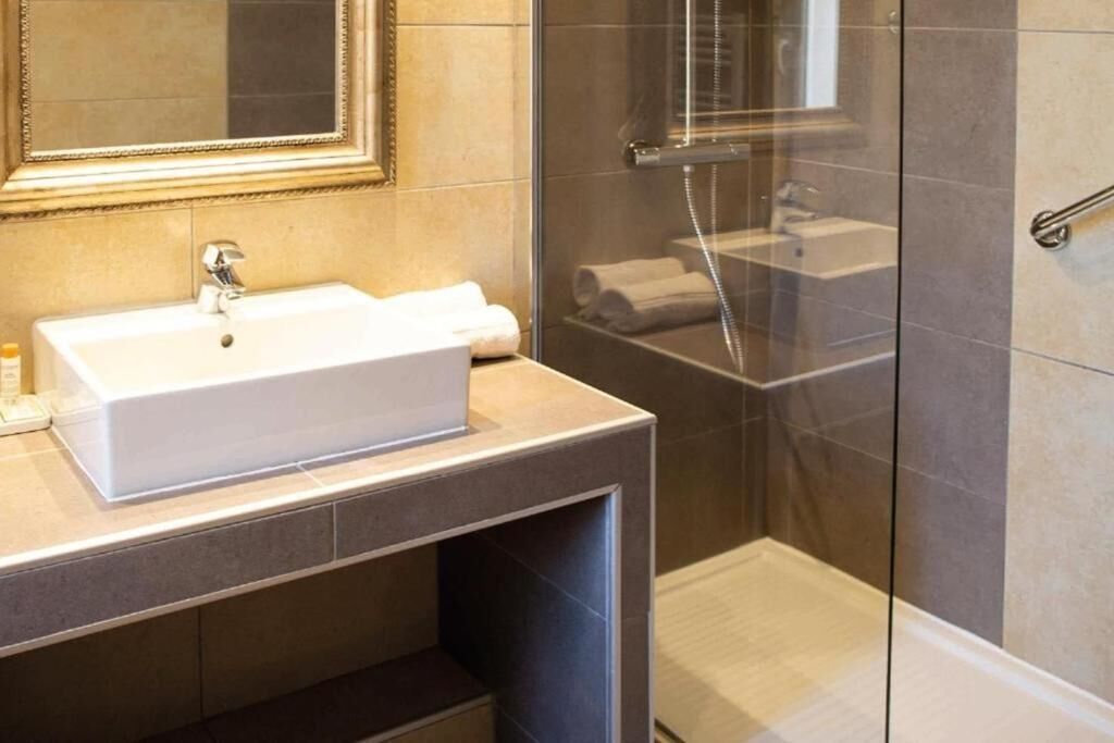 A bathroom with a white sink, a mirror, and a glass shower enclosure.