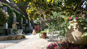 A courtyard with a stone pathway, a large planter, and a metal bench. - Hôtel La Casa Païral (Collioure)