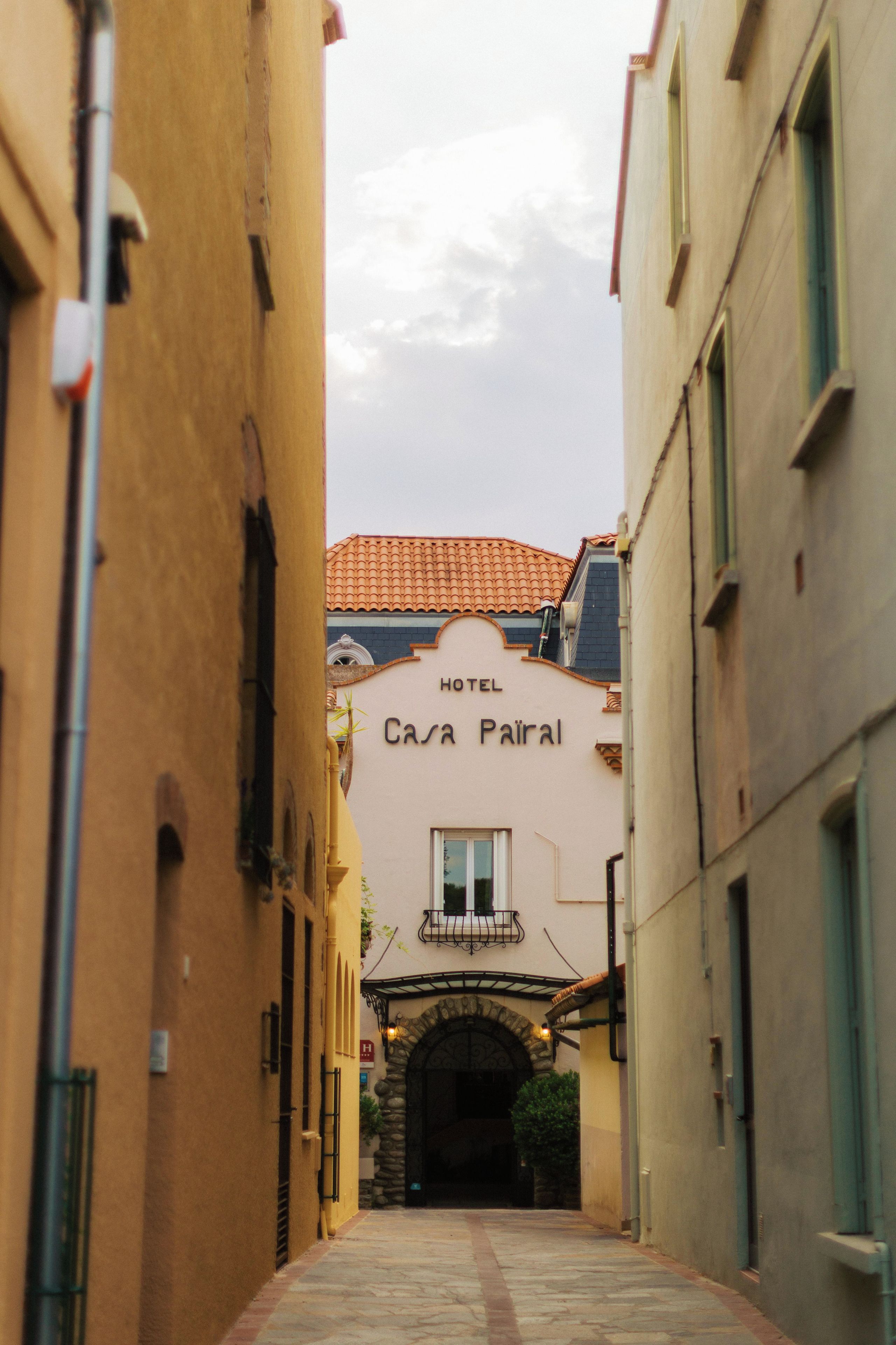 A narrow alleyway leading to a building with a sign reading 'HOTEL CASA PAIRAL.'