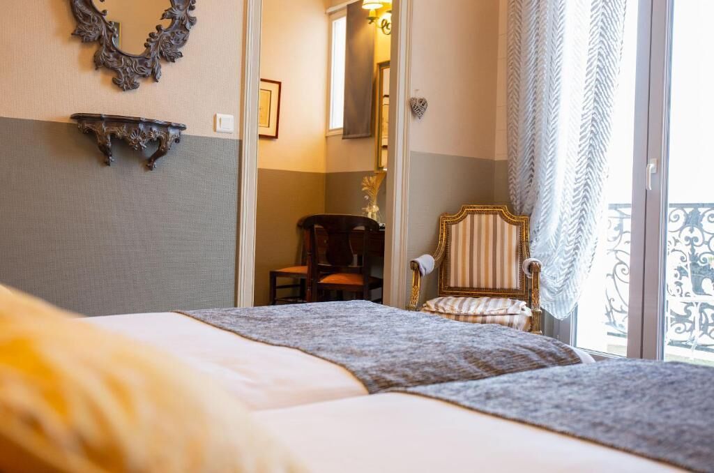 A hotel room with a bed, a chair, a mirror, and a balcony with a railing.