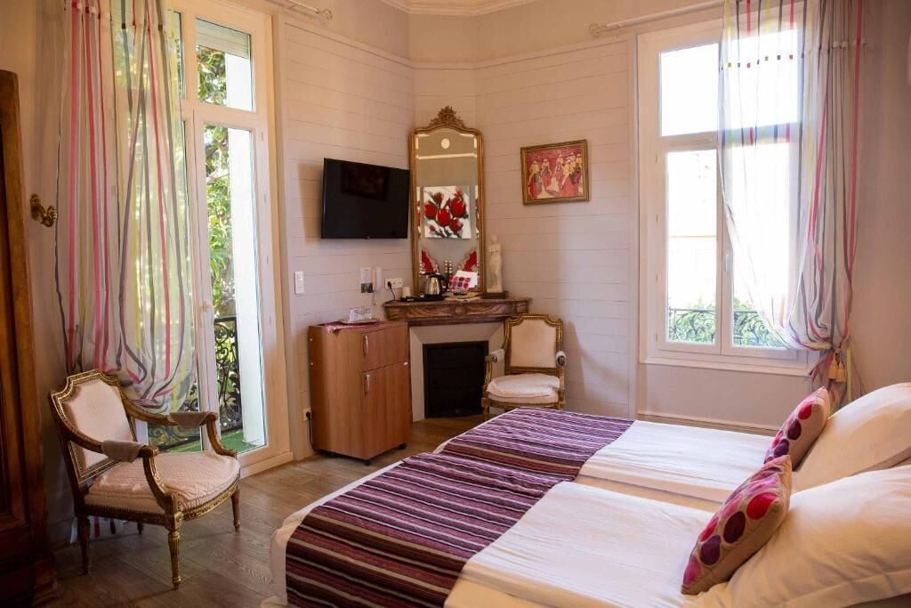 A bedroom with a bed, a chair, a desk, a mirror, and a television.