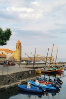 Un puerto con barcos, un faro y un edificio de piedra con una torre.