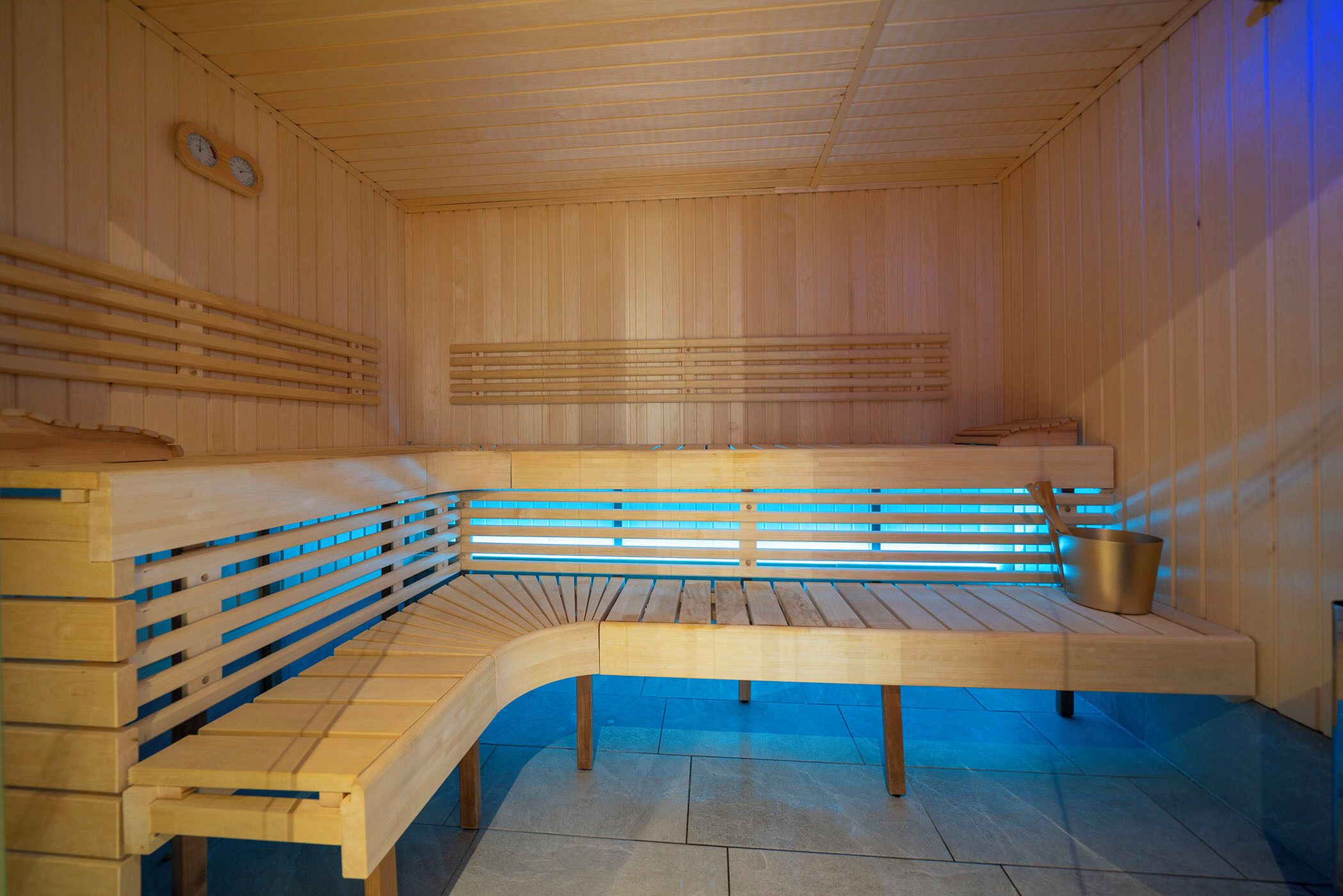 Una sauna de madera con bancos y un cubo.