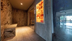 A hallway with marble walls, a wooden bench, and a glass door leading to an outdoor area.