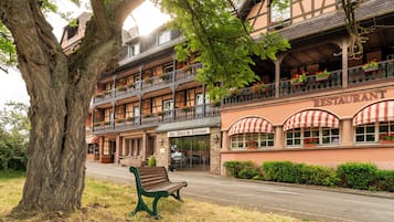 Un edificio de estilo europeo tradicional con un restaurante en la planta baja, que cuenta con un balcón con jardineras y una banca en el exterior.