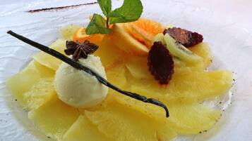 Une assiette de dessert avec des fruits coupés en tranches et une boule de glace à la vanille.