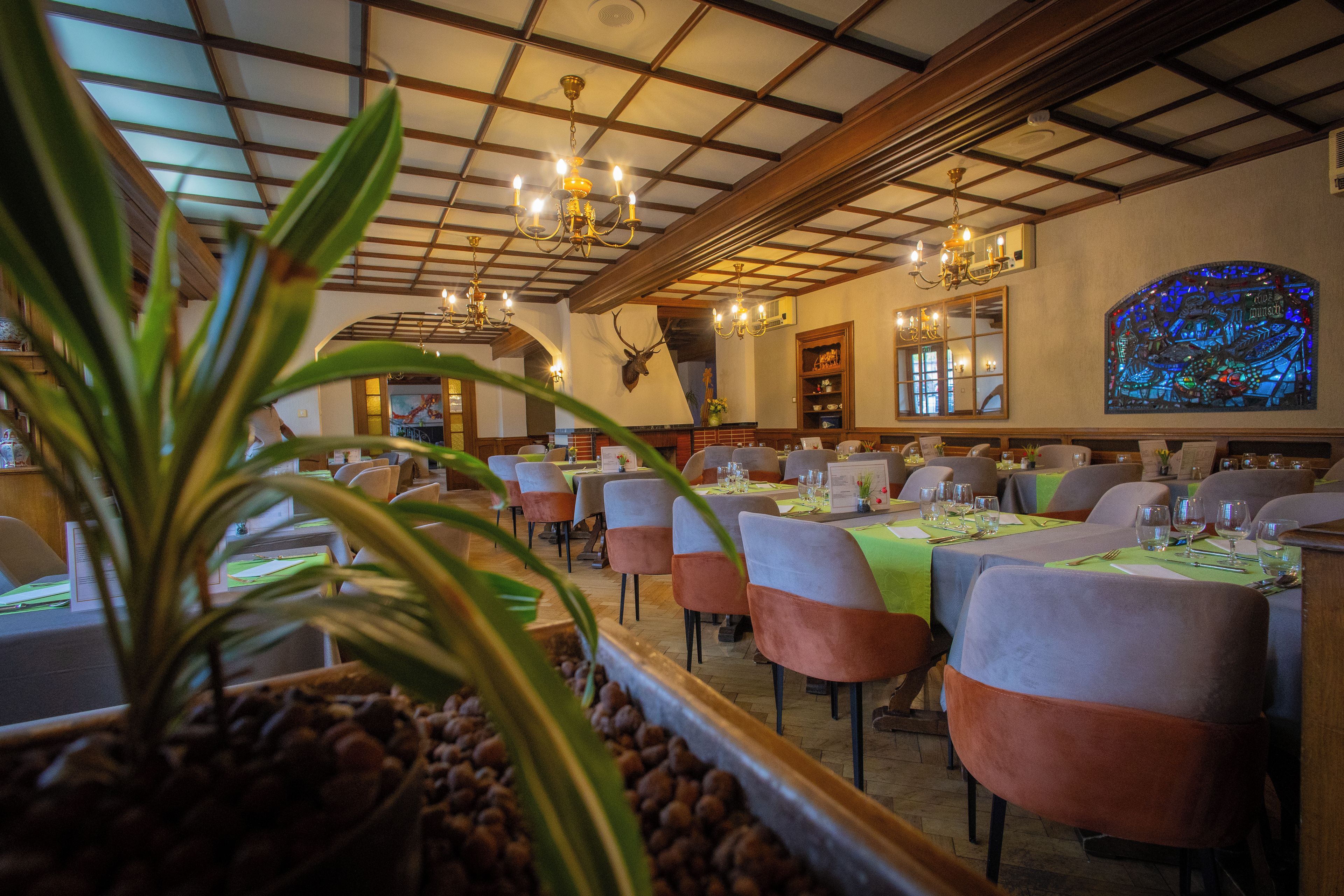 A restaurant interior with multiple dining tables, chairs, and a chandelier.
