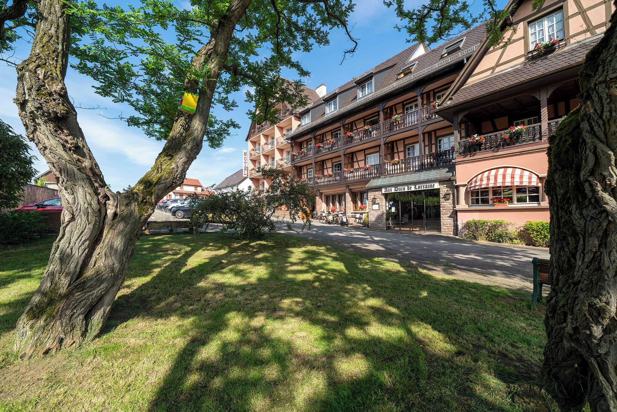 A traditional European building with multiple balconies, a well-maintained lawn, and a clear sky.