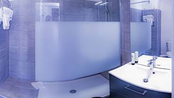 A modern bathroom with a glass-enclosed shower, a white sink, and a toilet.