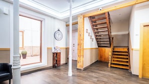 A spacious room with a wooden staircase, a wall clock, and a door labeled '201'. - Hostal El Pilar (Madrid)