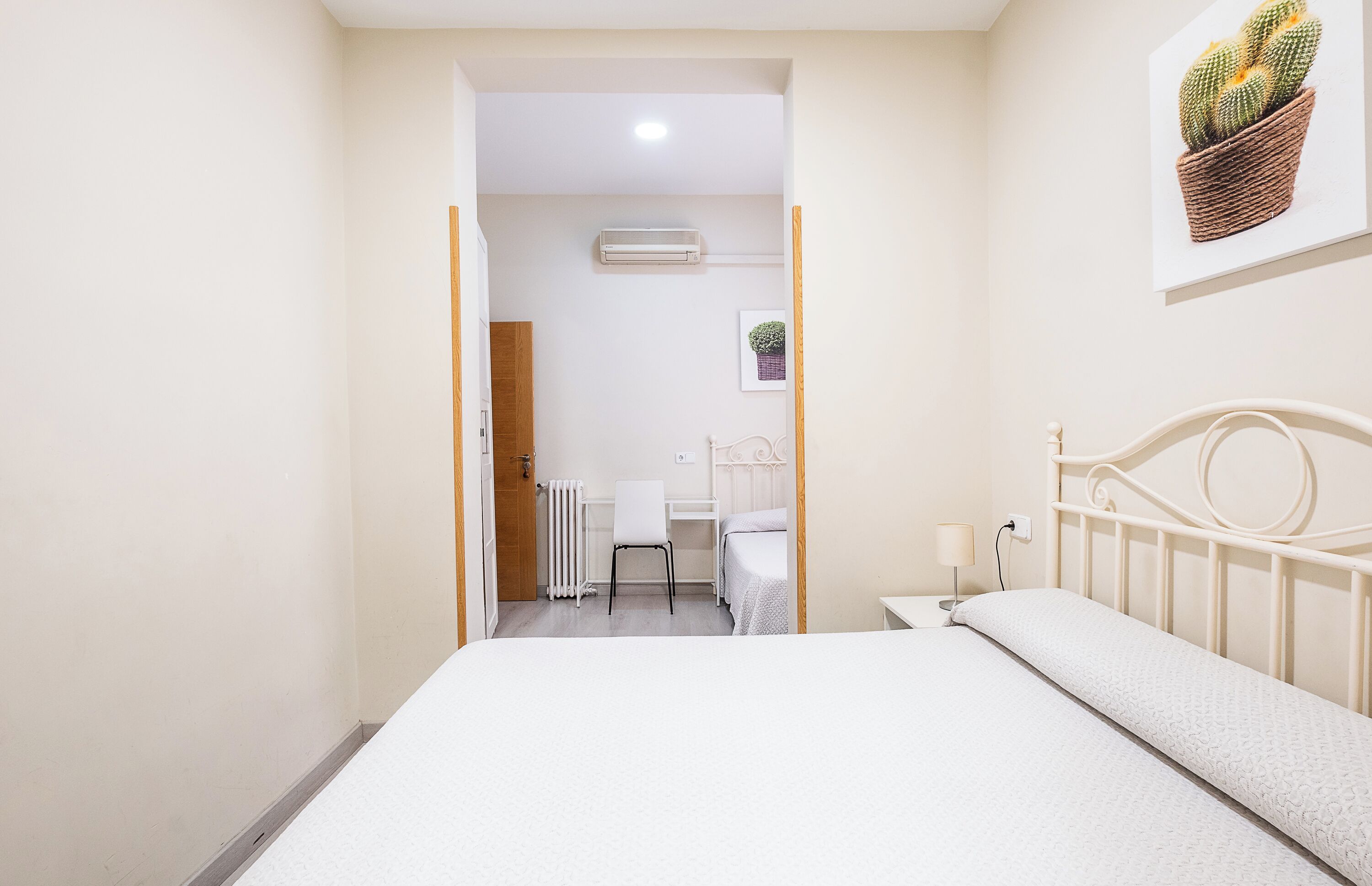 A bedroom with a bed, a desk, a chair, and a radiator.