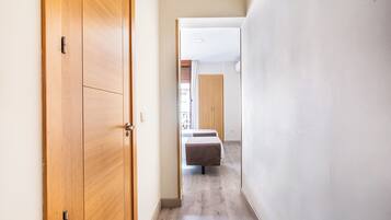 Un pasillo con puerta de madera, cama y armario.