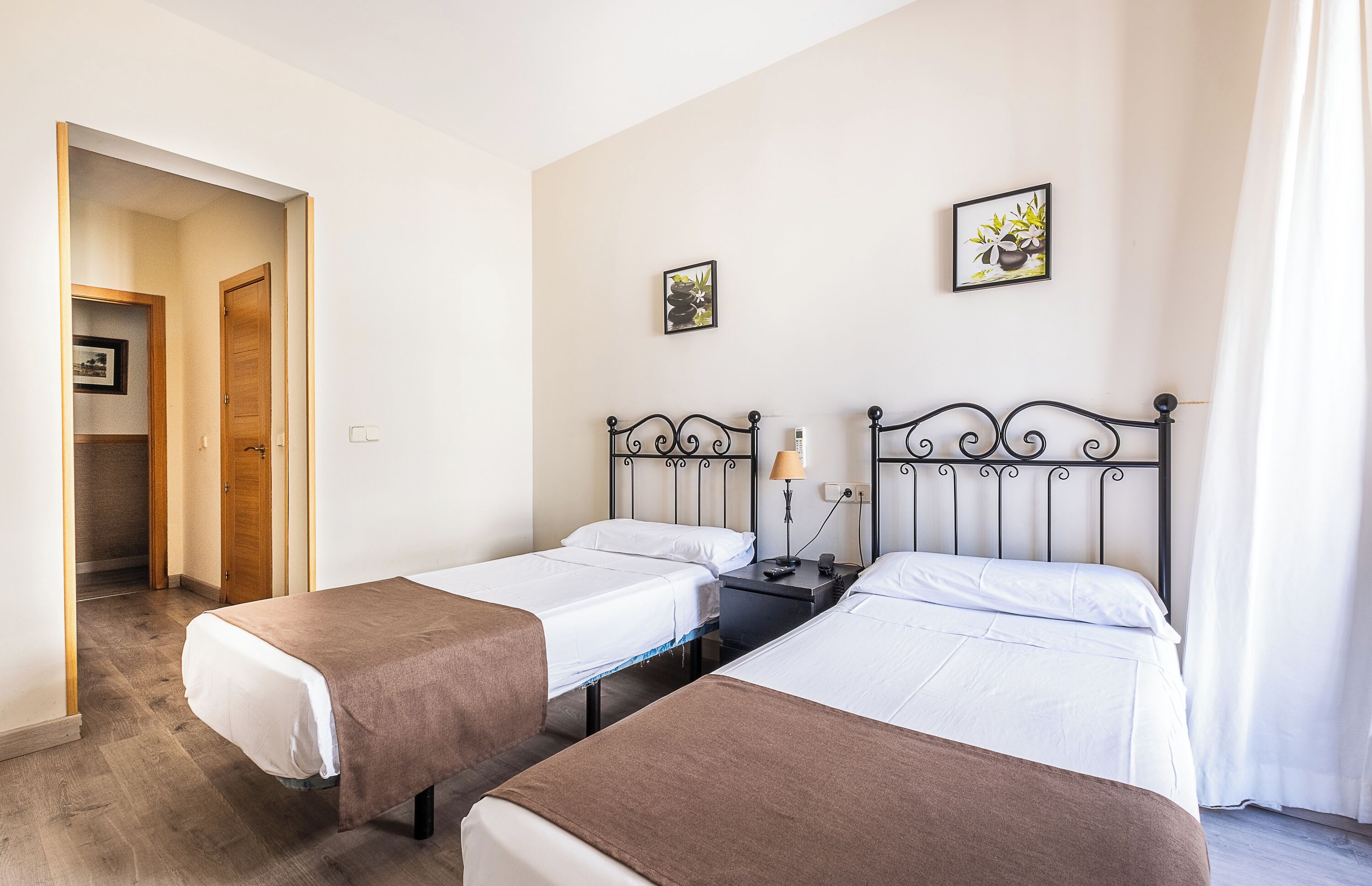 Een hotelkamer met twee enkele bedden, een nachtkastje met een lamp en een klein nachtkastje.