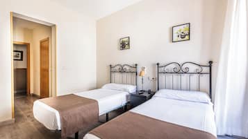 Een hotelkamer met twee enkele bedden, een nachtkastje met een lamp en een klein nachtkastje.