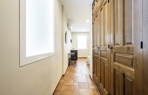 A hallway with a large window, a wooden wardrobe, and a desk with chairs. - Hostal El Pilar (Madrid)