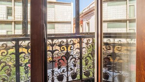 A view through a window with ornate iron railings, a clear sky, and buildings with balconies in the background. - Hostal El Pilar (Madrid)