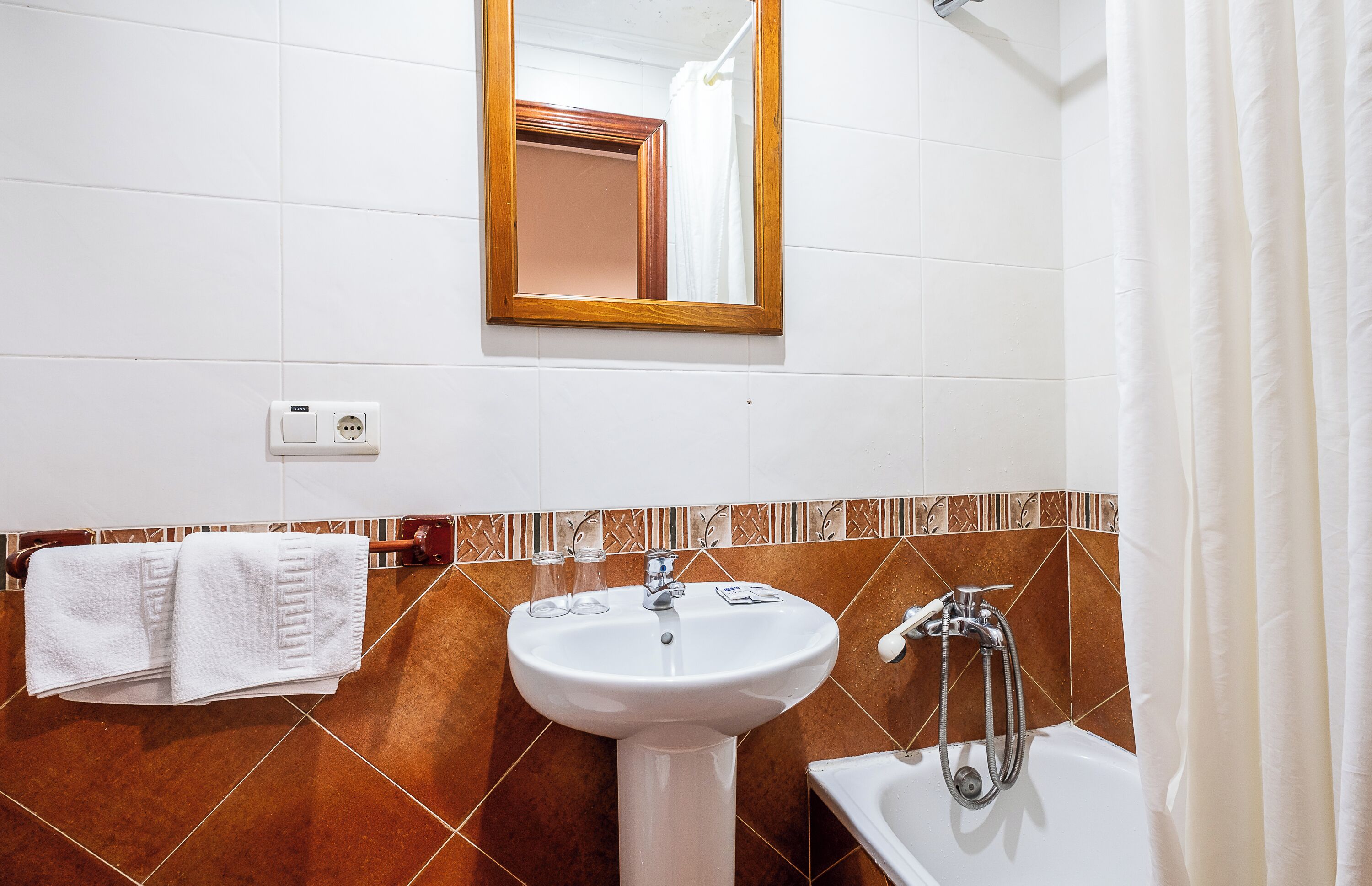 Un baño con lavamanos, espejo y ducha.