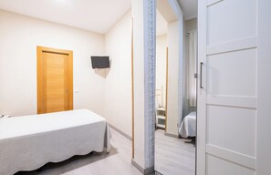A bedroom with a single bed, a wooden door, and a white wardrobe. - Hostal El Pilar (Madrid)