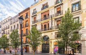 Una calle con edificios de varios pisos, una farola y árboles.