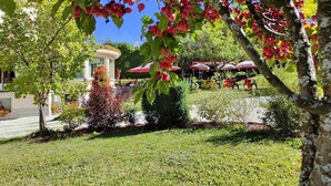 Un jardín con una fuente, mobiliario exterior y un edificio con balcón.