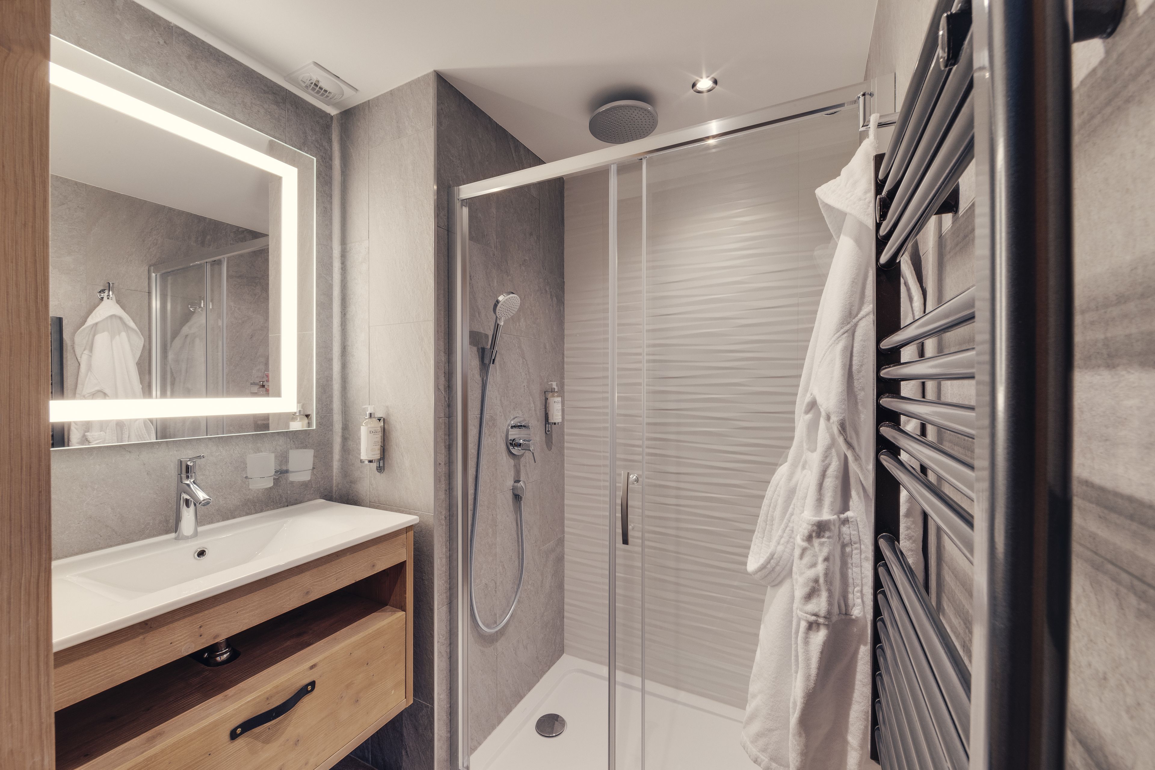 Een moderne badkamer met een douche met glazen wand, een wastafel met spiegel en een handdoekrek.