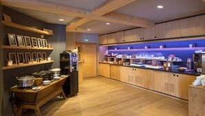 A modern kitchen with wooden cabinets, a built-in oven, and a buffet counter with various food items.