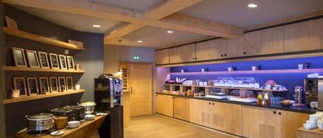 A modern kitchen with wooden cabinets, a built-in oven, and a buffet counter with various food items.