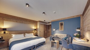 A modern bedroom with a large bed, a desk, and a chair. There are wooden walls and a blue accent wall.