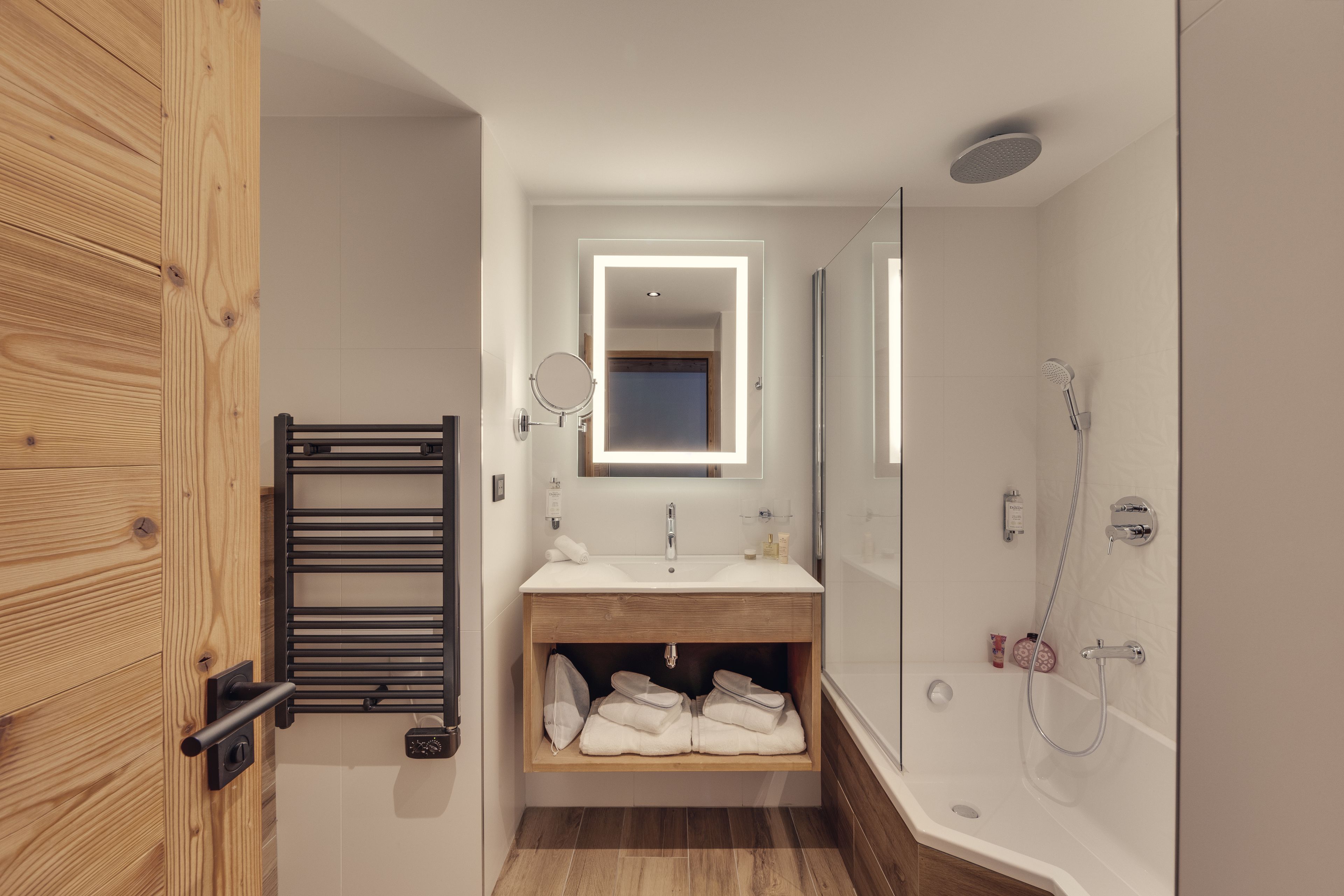 Een moderne badkamer met een houten wastafel, een spiegel, een douche en een handdoekhouder.
